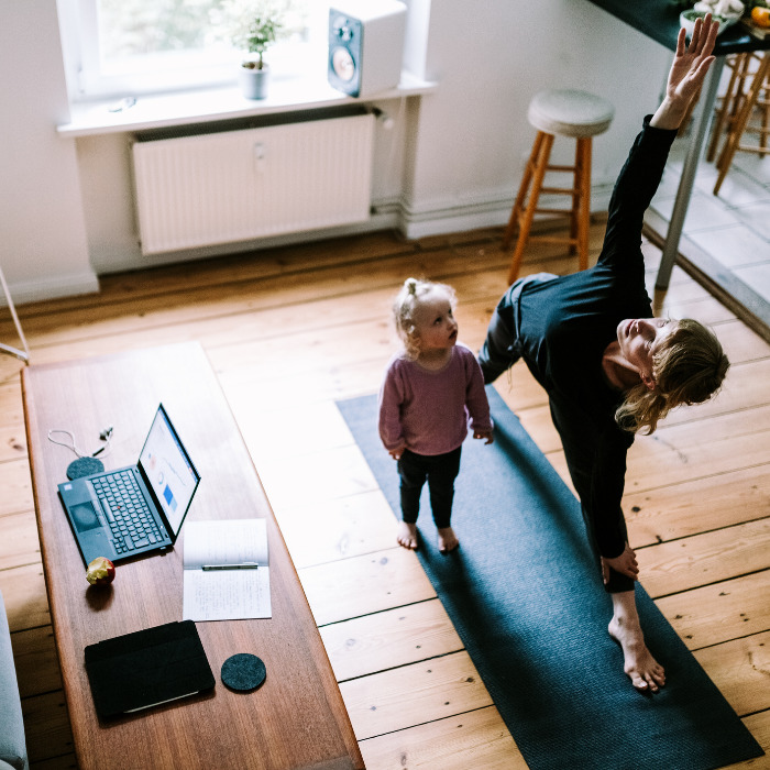 woman stretching and exercising at home with kid while working remotely